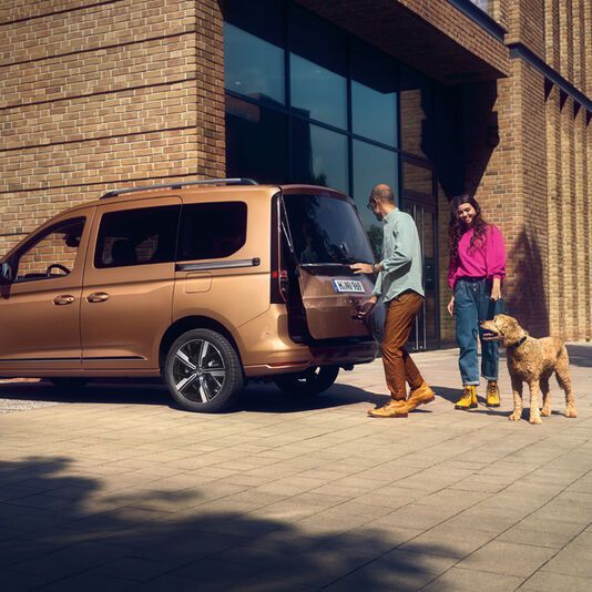 VW Caddy Kastenwagen Stadt weiß Ein weißer Caddy Kastenwagen fährt dynamisch durch eine belebte Stadt.